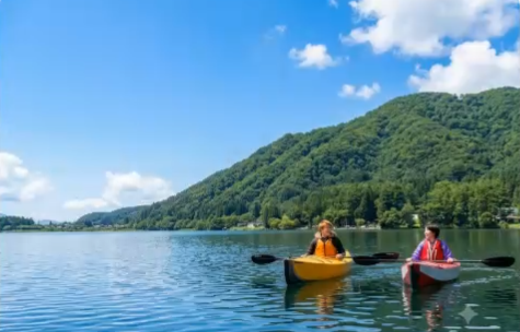 青空と新緑の山を背景に青木湖でカヤックを楽しむ様子